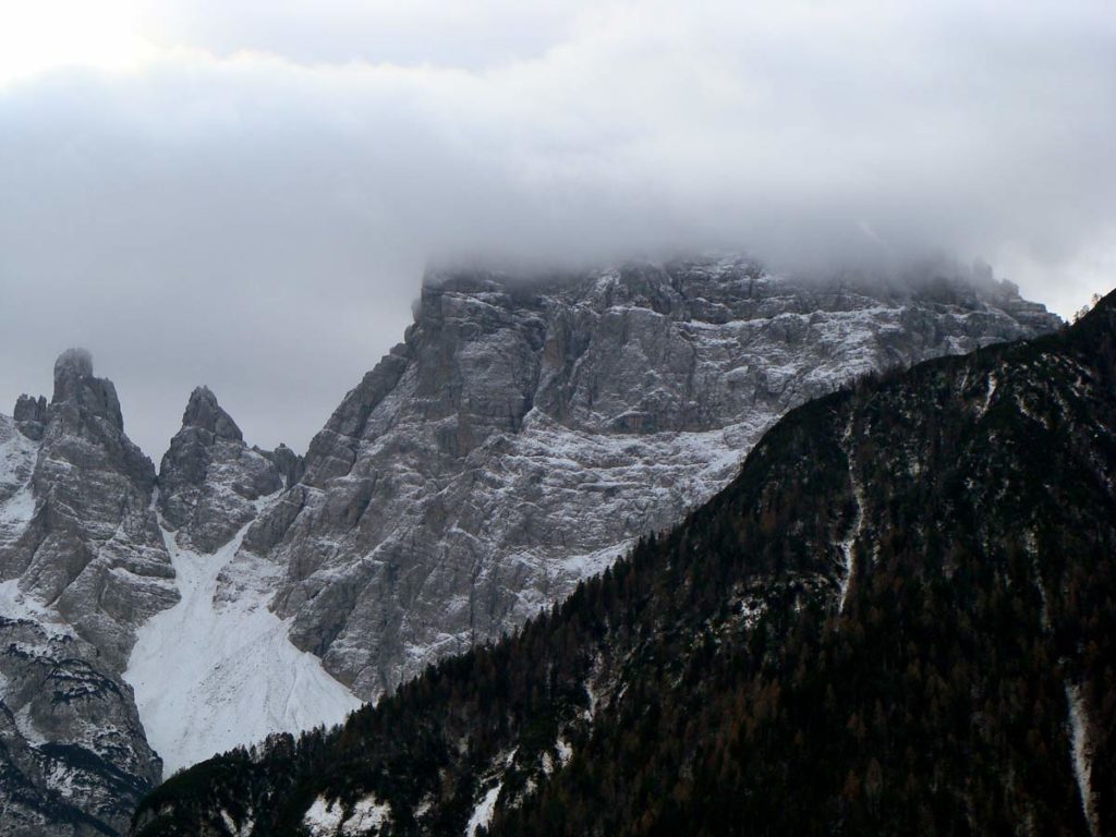 Torre Cridola, Torre Both e M. Cridola con la sommità avvolta dalle nuvole; in primo piano le pendici boscate del Col de la Cros