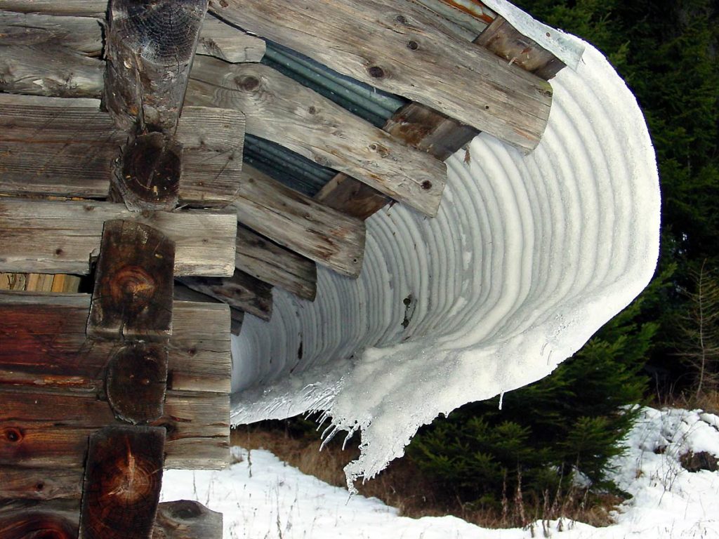 Tipico e curioso scivolamento della neve da una copertura in lamiera di un tabià